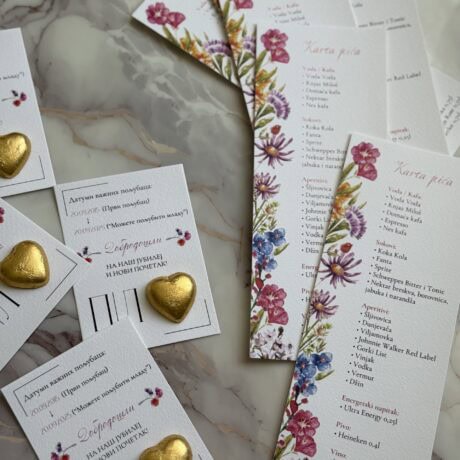 Vibrant floral-themed wedding menu and table cards with gold heart decorations, perfect for elegant event decor.
